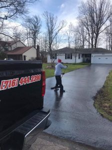 Worker seal coating a driveway