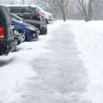 Line of cars parked in snow covered parking lot